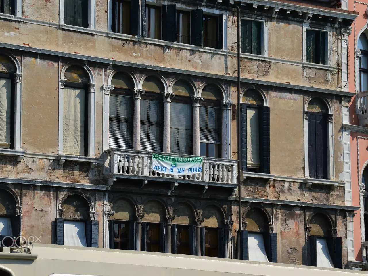 L'immagine mostra un edificio vecchio con molte finestre e balconi a Venezia, Italia. In fondo...