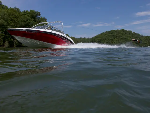 In questa immagine un uomo che fa wake surfing dietro il motoscafo sul fiume sullo sfondo ci sono...