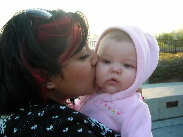 Al centro dell'immagine una donna sta abbracciando un bambino. Sullo sfondo dell'immagine ci sono...