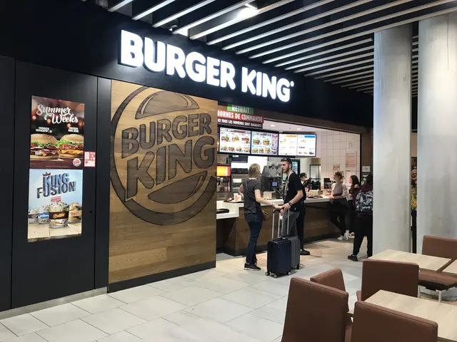 L'immagine mostra un ristorante Burger King all'aeroporto, con un gruppo di persone in piedi sul...