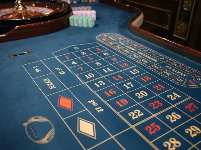 L'immagine mostra un tavolo della roulette in un casinò, con un panno blu che copre il tavolo e una...