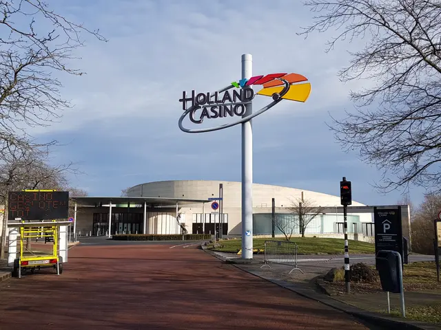 L'immagine mostra il Holland Casino a Londra, Inghilterra, con una strada in primo piano, erba a...