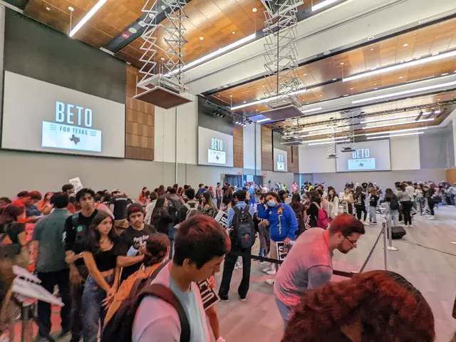 L'immagine mostra un gruppo di persone in piedi in una stanza con una parete sullo sfondo, schermi...