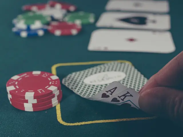 L'immagine mostra una mano che tiene una coppia di assi su un tavolo verde, circondata da monete...